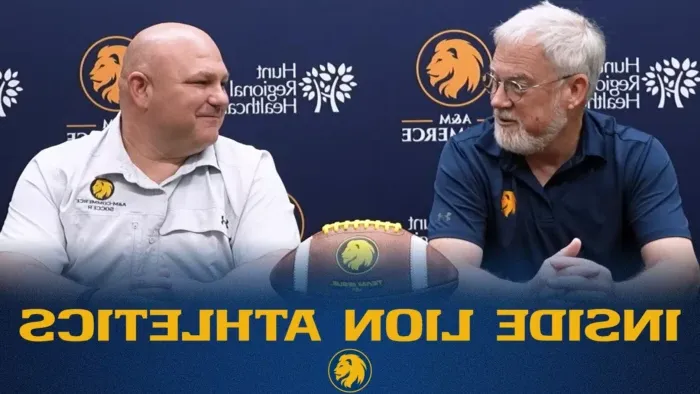 Podcast host and interviewee sit beside each other with football on the table between them. Backdrop behind them is blue with lion head logo and "Hunt Regional Healthcare" logo.