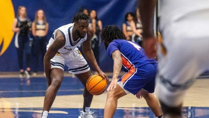 Player in white uniform on the right dribbles the ball. Player in blue uniform on the left defends the ball.